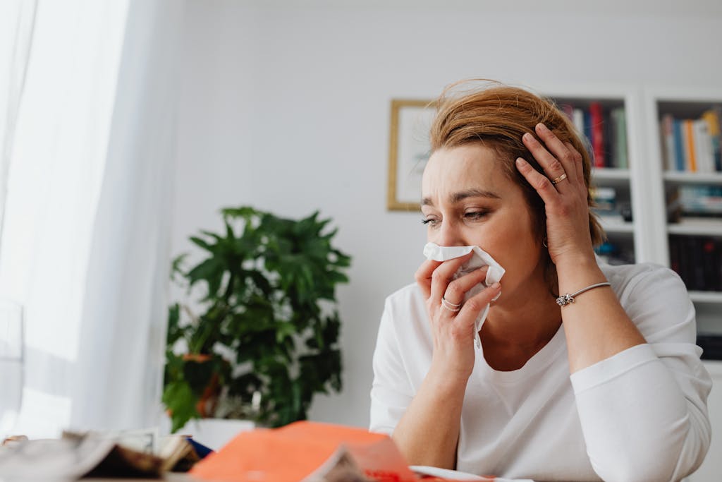 Recomendaciones para la prevención de alergias en primavera. 2 An adult woman feeling unwell, blowing her nose indoors.